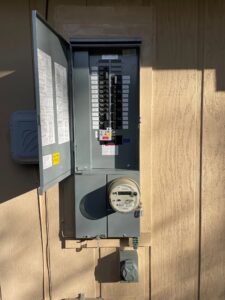 A gray electrical panel sitting on top of a wooden wall.