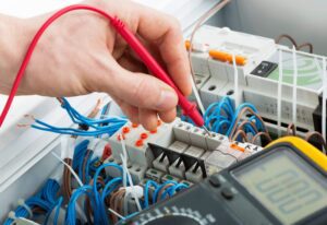 A person is working on wires in an electrical panel.