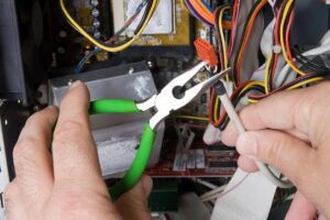 A person holding some green pliers and wires